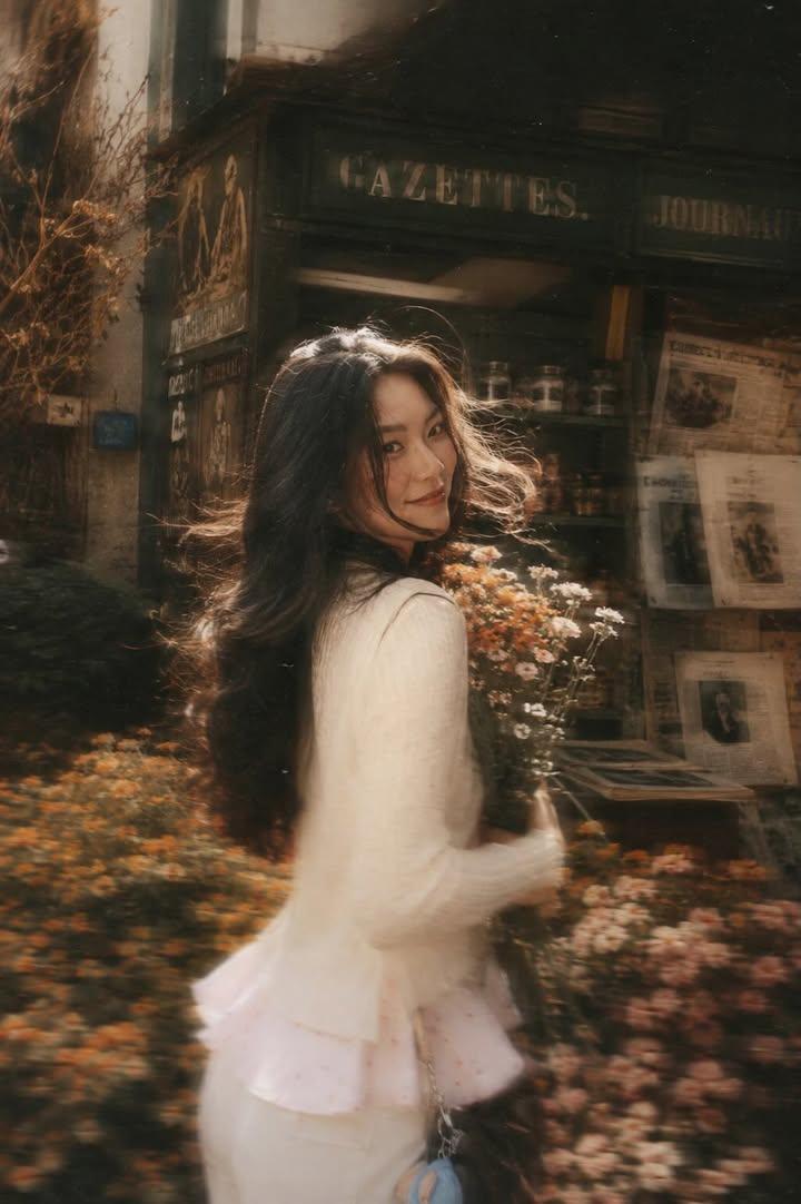 A beautiful young woman with long dark flowing hair holding a bouquet…