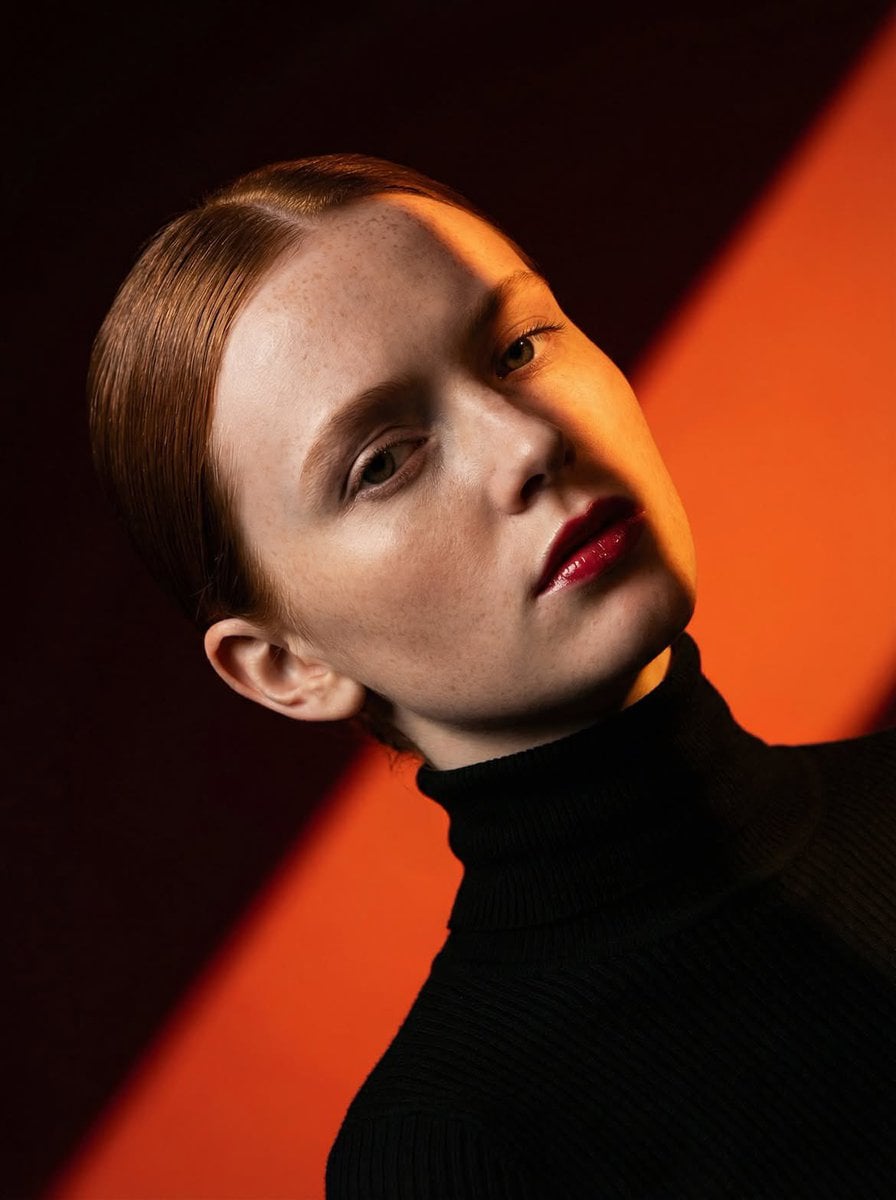 Ultra-high-fashion editorial beauty portrait of a fair-skinned female model with sleek center-parted hair tig…