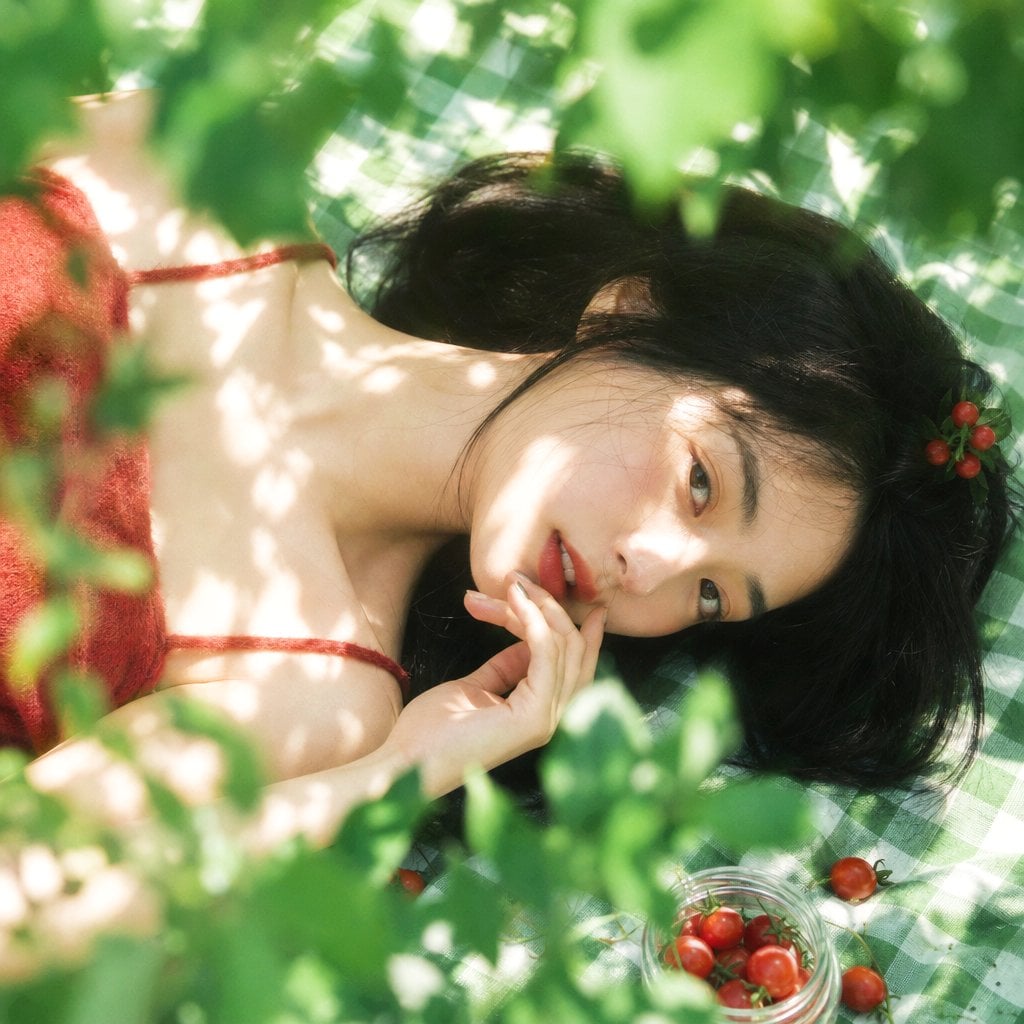 真人摄影，夏日植物系生活方式写真，清透日系胶片感，竖幅 2:3，俯拍近景到面部特写，年轻女性横向躺在绿白格纹野餐布上，脸部位于画面中部偏右…