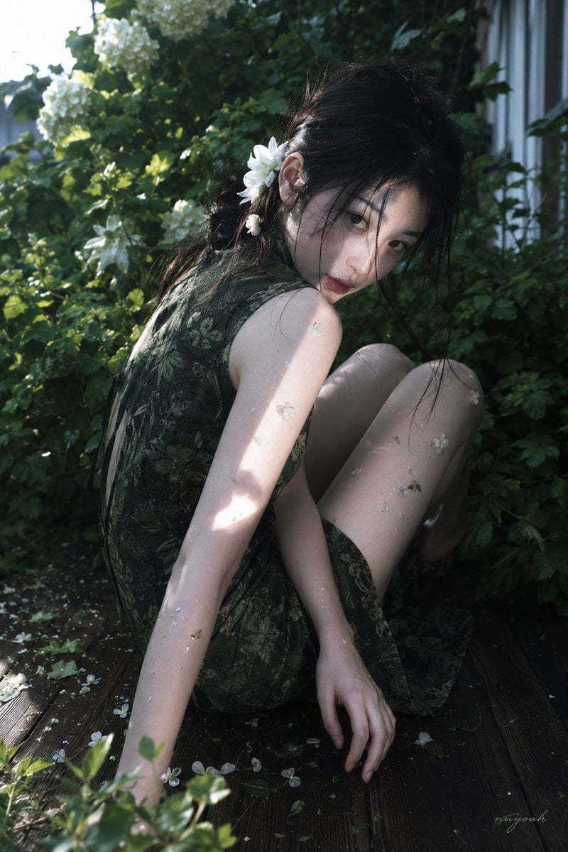 真人摄影，真实人物，户外花园唯美人像写真，低饱和冷绿调与斑驳自然光，轻微胶片柔焦和电影感。竖幅近中景，略高机位俯拍，人物占画面约70%，身…