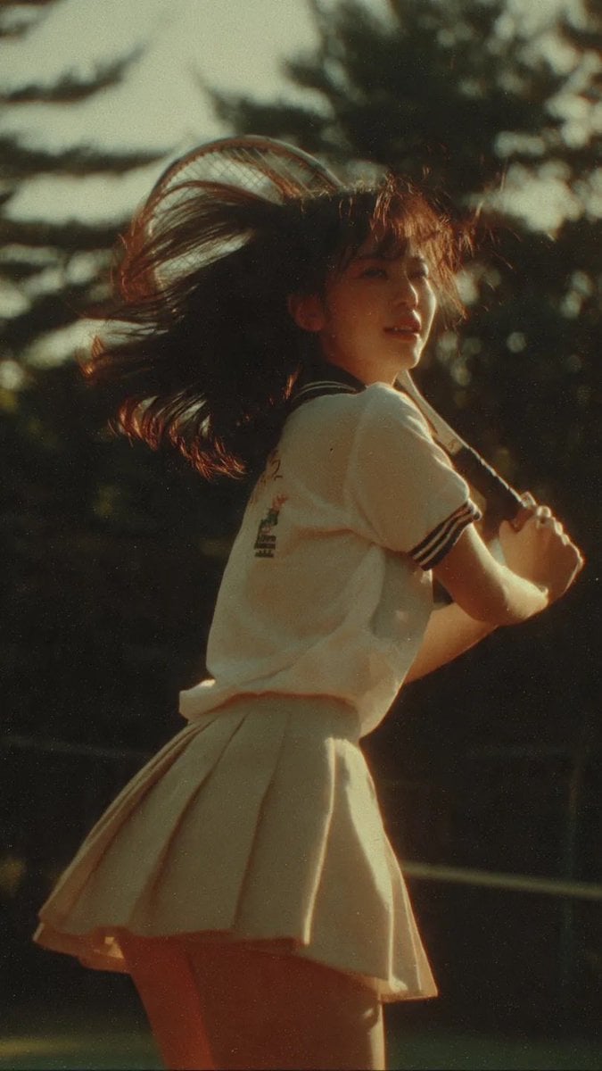 Cinematic middle shot of a Japanese teenage girl in tennis uniform, c…